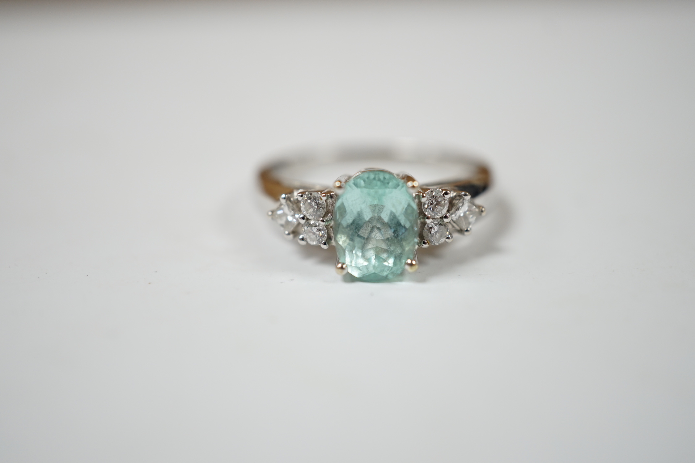 A modern 18ct gold and oval cut paraiba tourmaline set dress ring with six stone diamond set shoulders, size O, gross weight 4.9 grams.